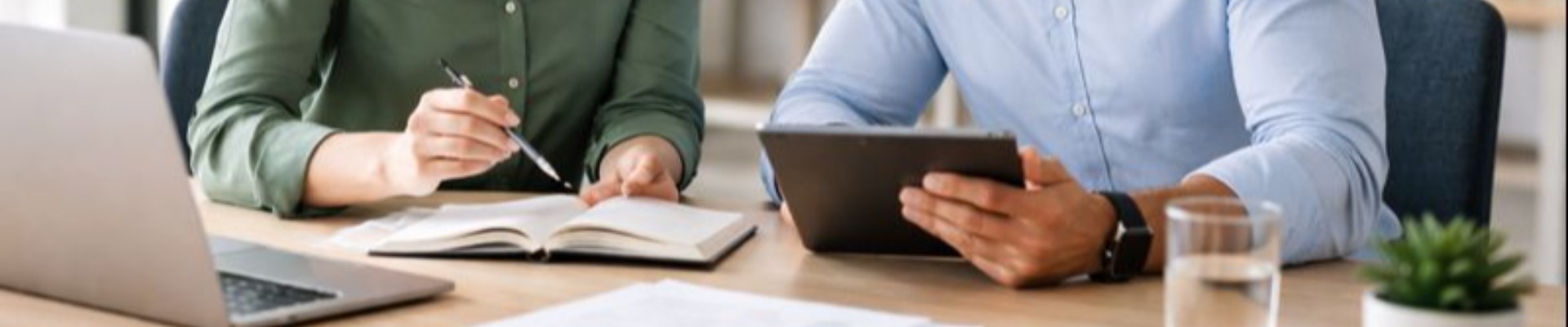 A man and woman meeting in a modern office workspace, reviewing information together on a laptop in a calm, professional setting.